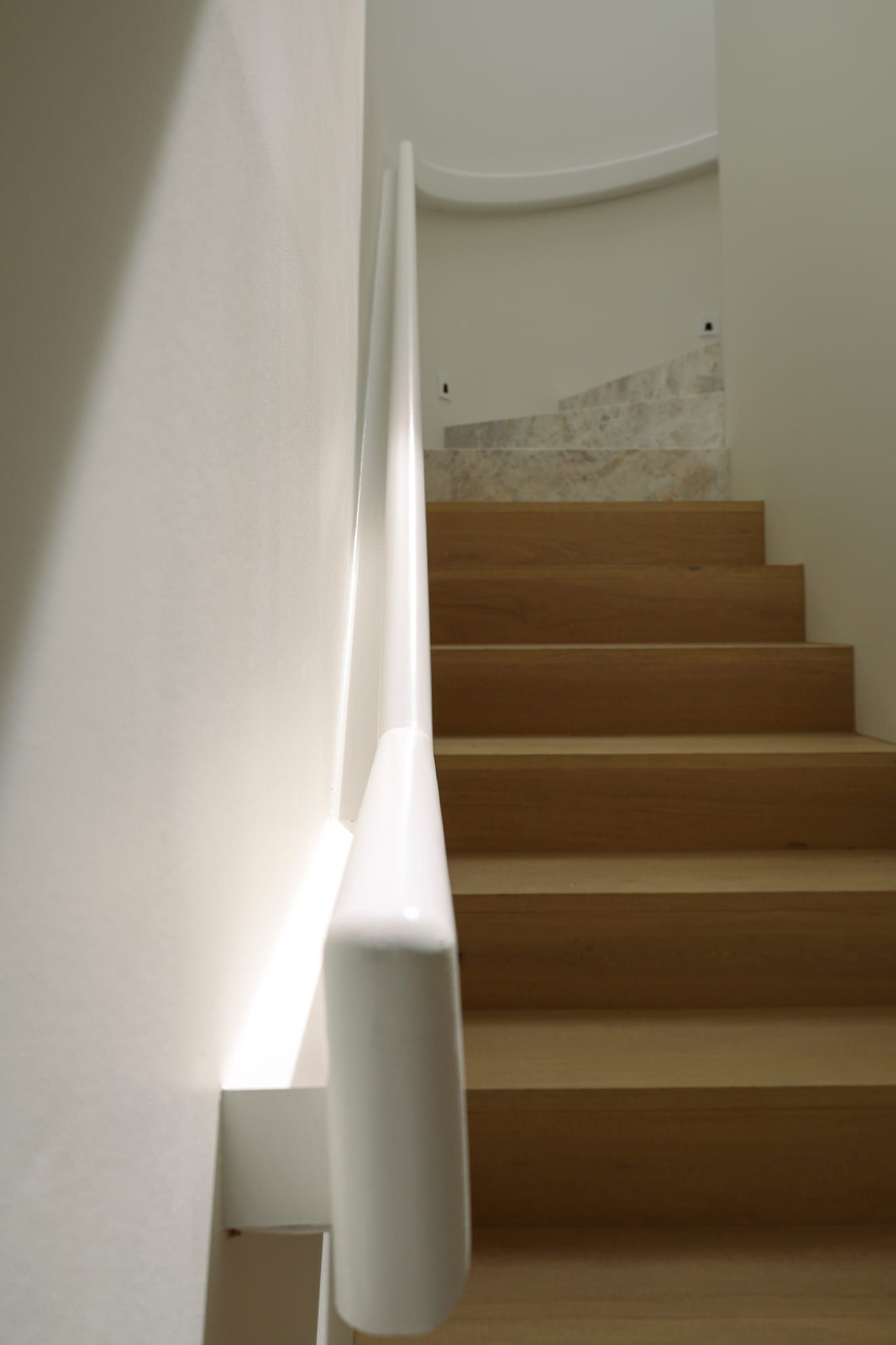 The sculpted plaster stair rising through curved walls