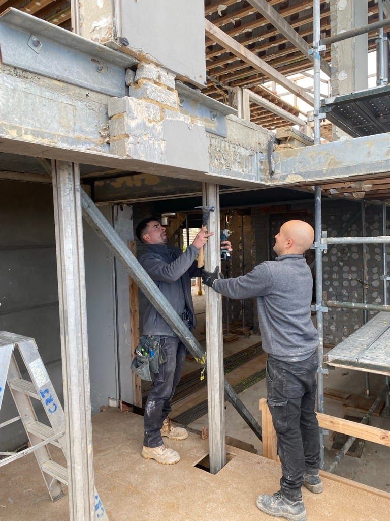 Two of the team installing a steel prop beneath a propped beam