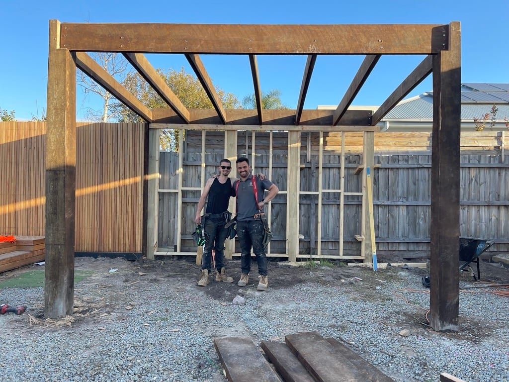Two of the Siji crew in front of a timber pergola they built, end of the day