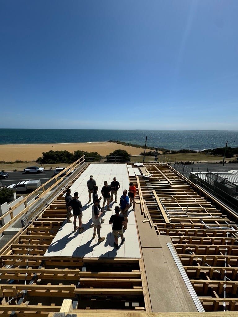 The Siji team on the first-floor deck of a coastal build, the bay behind them